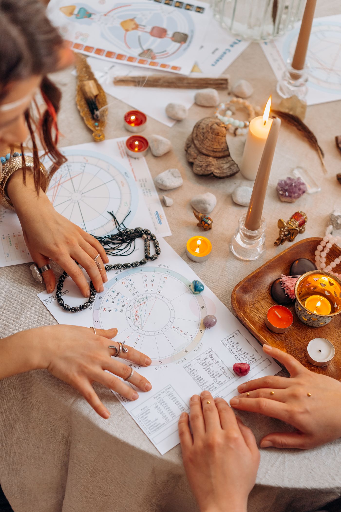 Hands arranging charts and candles on a table for a reflective reading