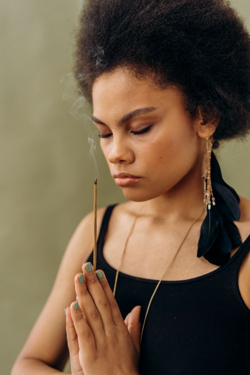 Free Woman meditating with closed eyes and incense, highlighting spiritual tranquility. Stock Photo