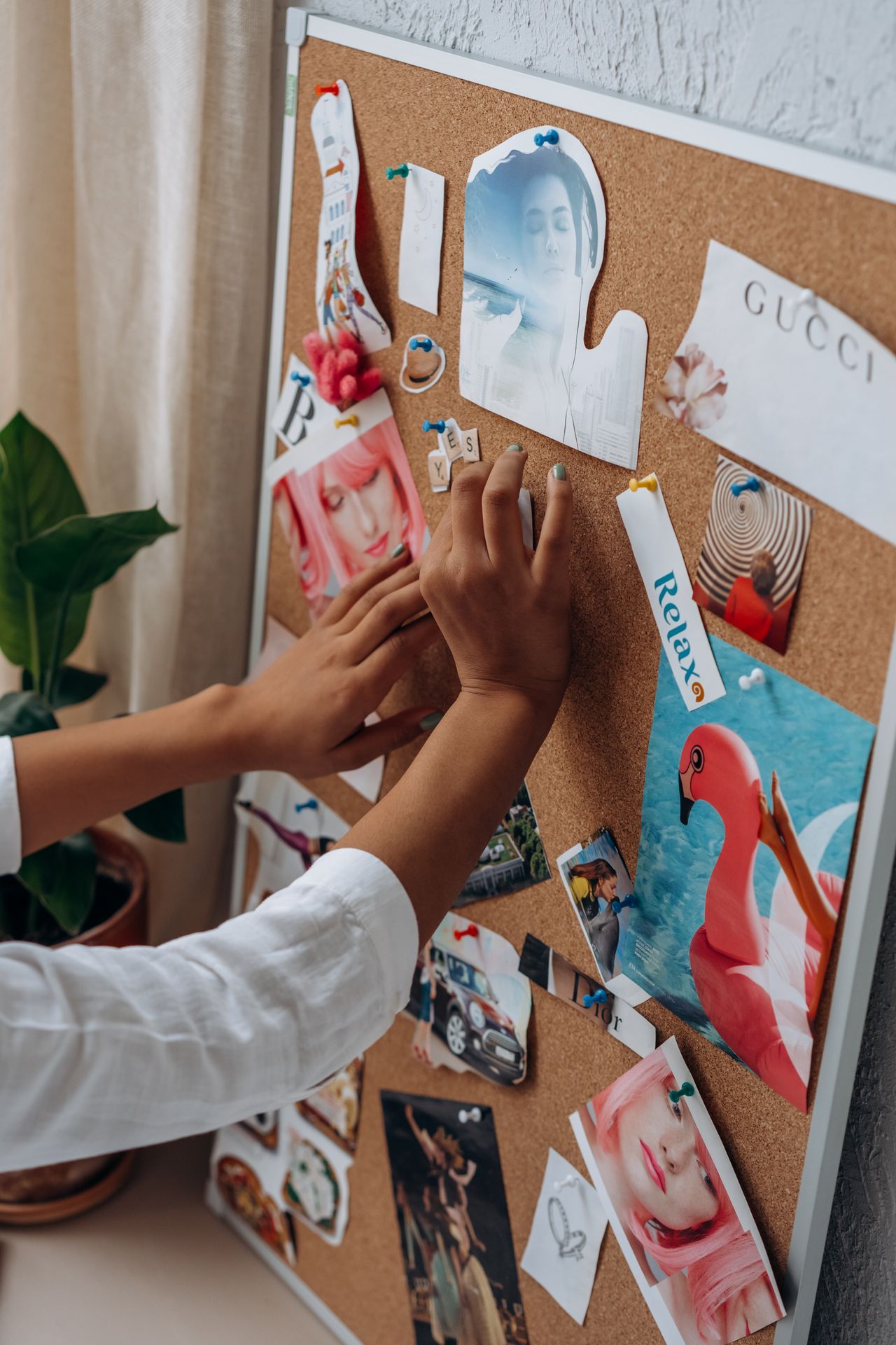 Aesthetic Digital Planner | Daily, Weekly & Monthly Planner A person arranges inspirational cut-outs on a cork board for a vision board project