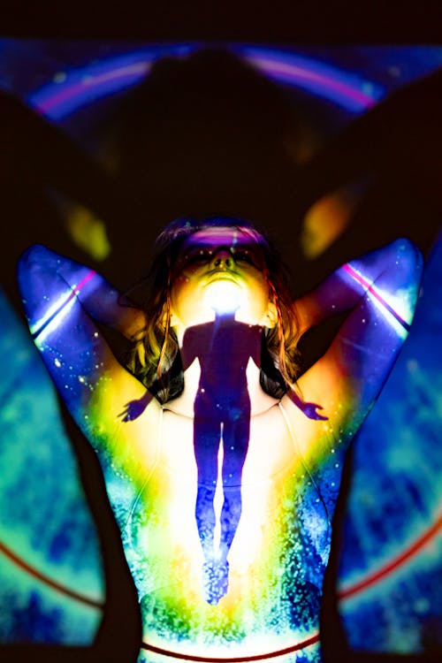 Free A silhouette emerges through colorful projections, evoking spirituality and energy. Stock Photo