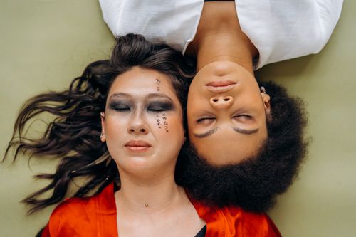 Free Serene portrait of two women lying head to head with eyes closed in contemplation. Stock Photo