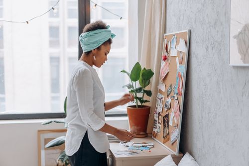Free Young woman with headscarf creating a vision board indoors. Inspiring workspace for creativity. Stock Photo