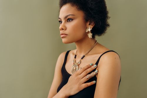 Free A stylish woman in elegant jewelry poses against a neutral background, exuding confidence. Stock Photo