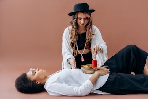 Woman in White Long Sleeve Shirt and Black Hat Sitting on Bed