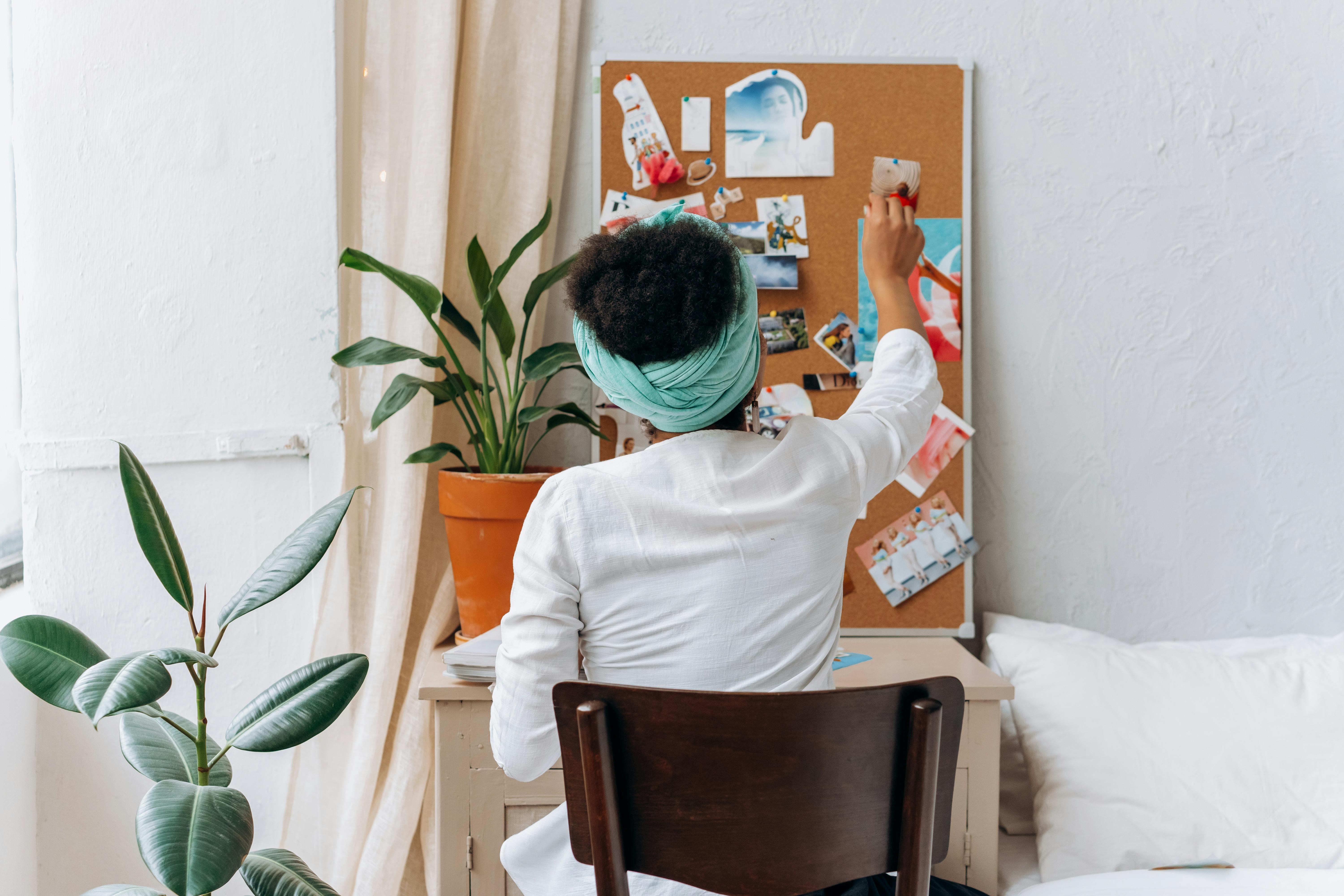 Free A woman in a cozy room organizing a vision board with photos and ideas. Stock Photo