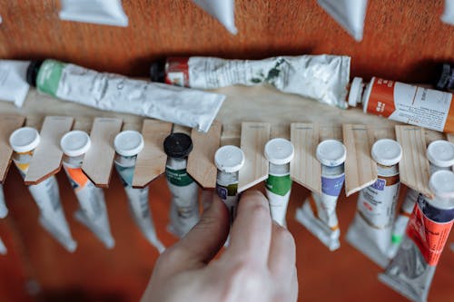 Person Holding White and Green Bottles