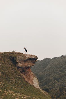 A person running on a mountain cliff edge, embodying thrill and adventure in the great outdoors.