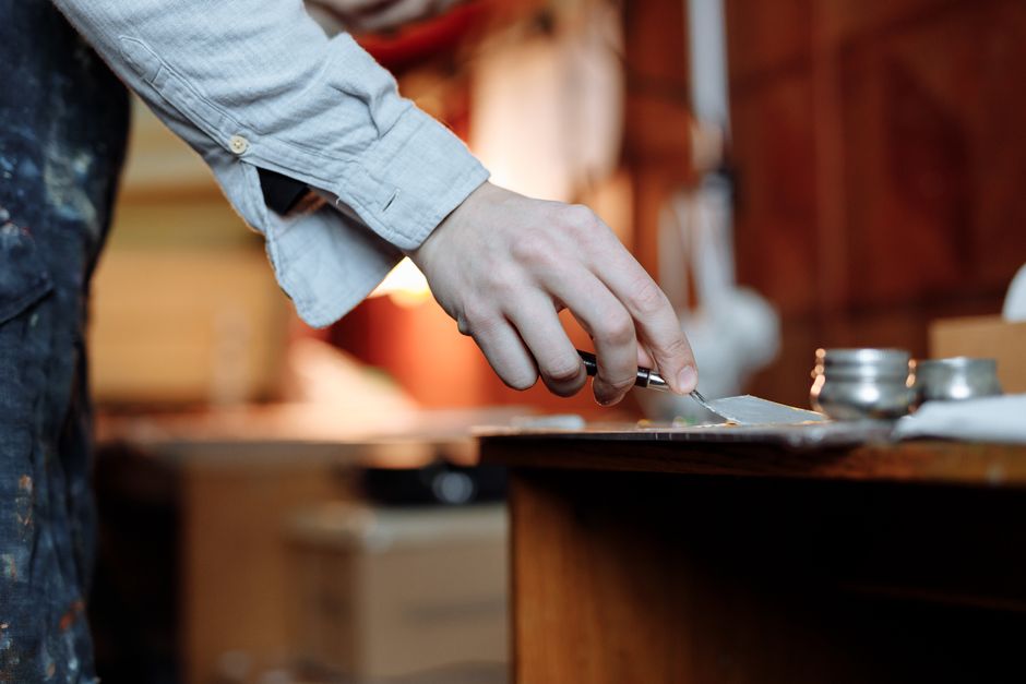 Artist's hand skillfully uses a palette knife indoors for fine art creation.