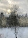 Icy transparent window overlooking residential buildings on street of city on blurred background on cold winter day
