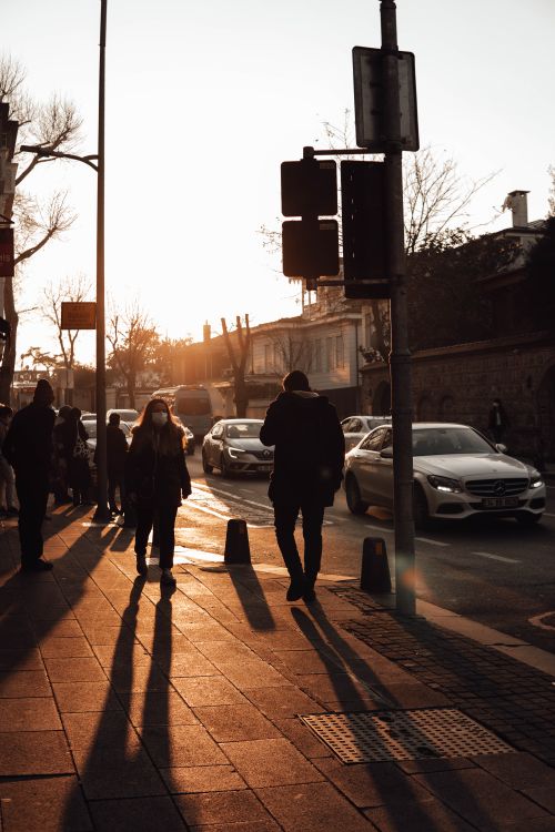 Free Unrecognizable people in outerwear and medical masks standing at crosswalk in city in evening Stock Photo