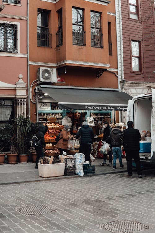 Customers buying food products in street shop near old building and car in city