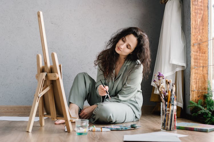 Person Sitting On The Floor While Holding A Paintbrush