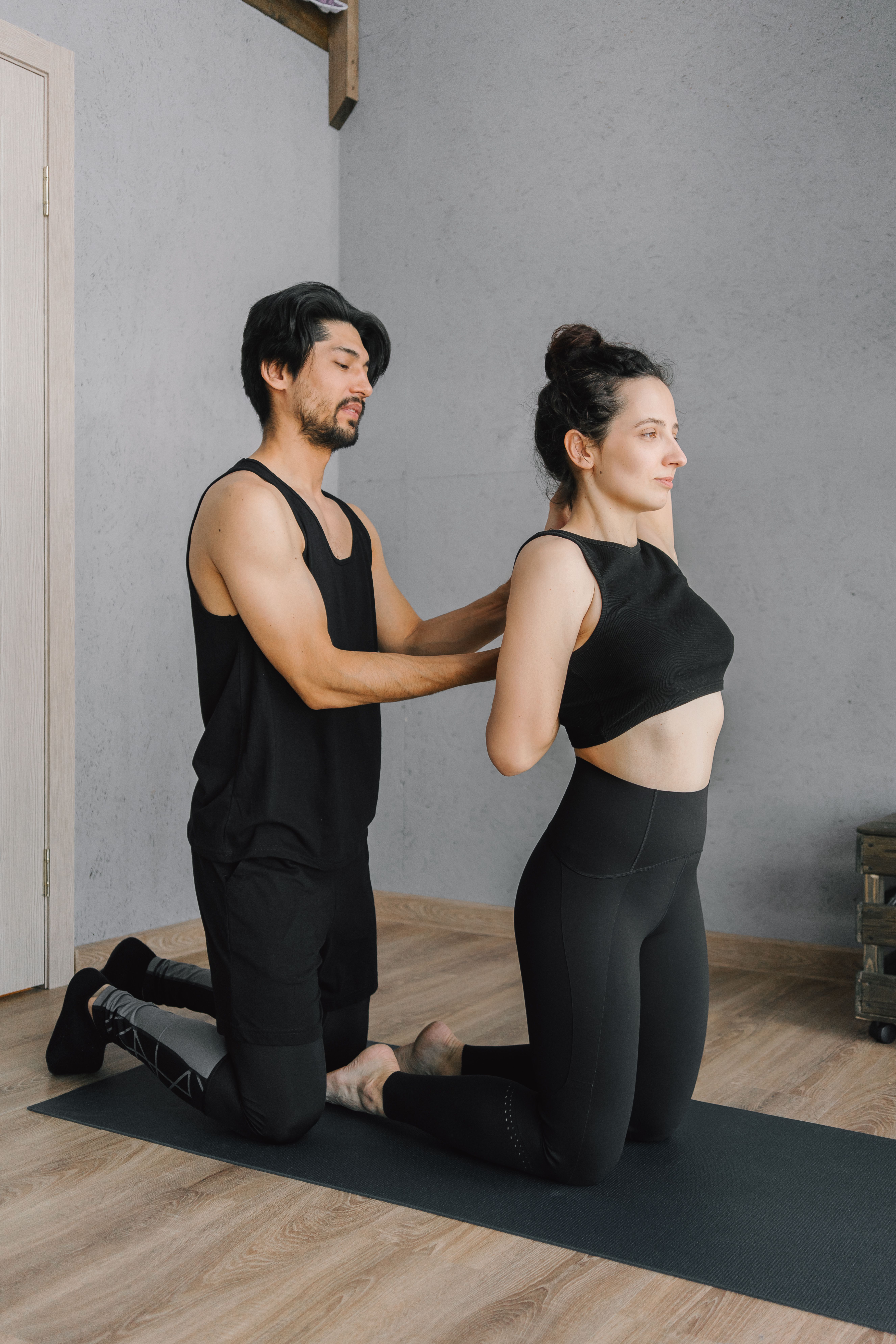 trainer helping woman adjust posture in studio
