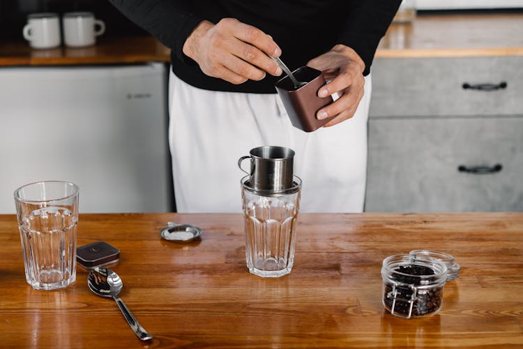 Person Making Coffee On A Glass Cup