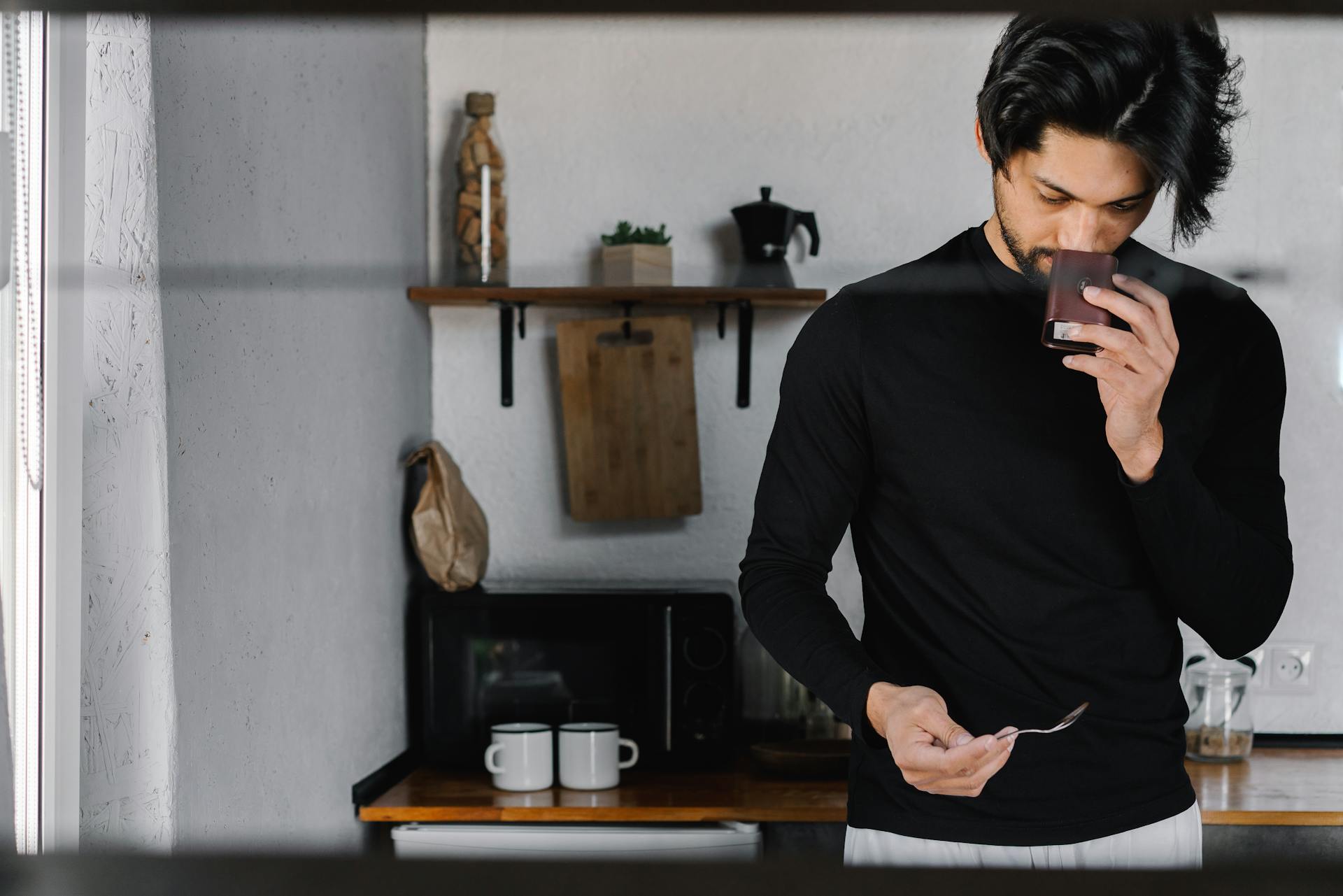 A Man in Black Long Sleeves Smelling the Container he is Holding