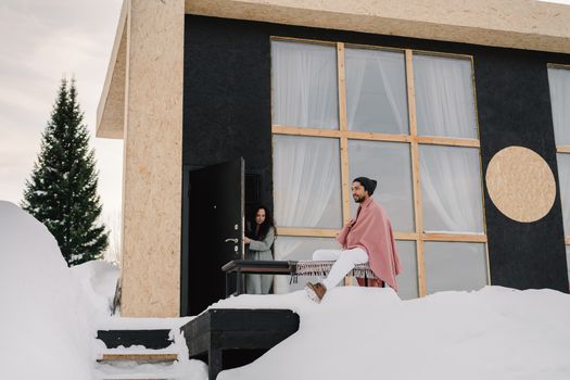 Contemporary house in a snowy setting with two people enjoying a winter day.