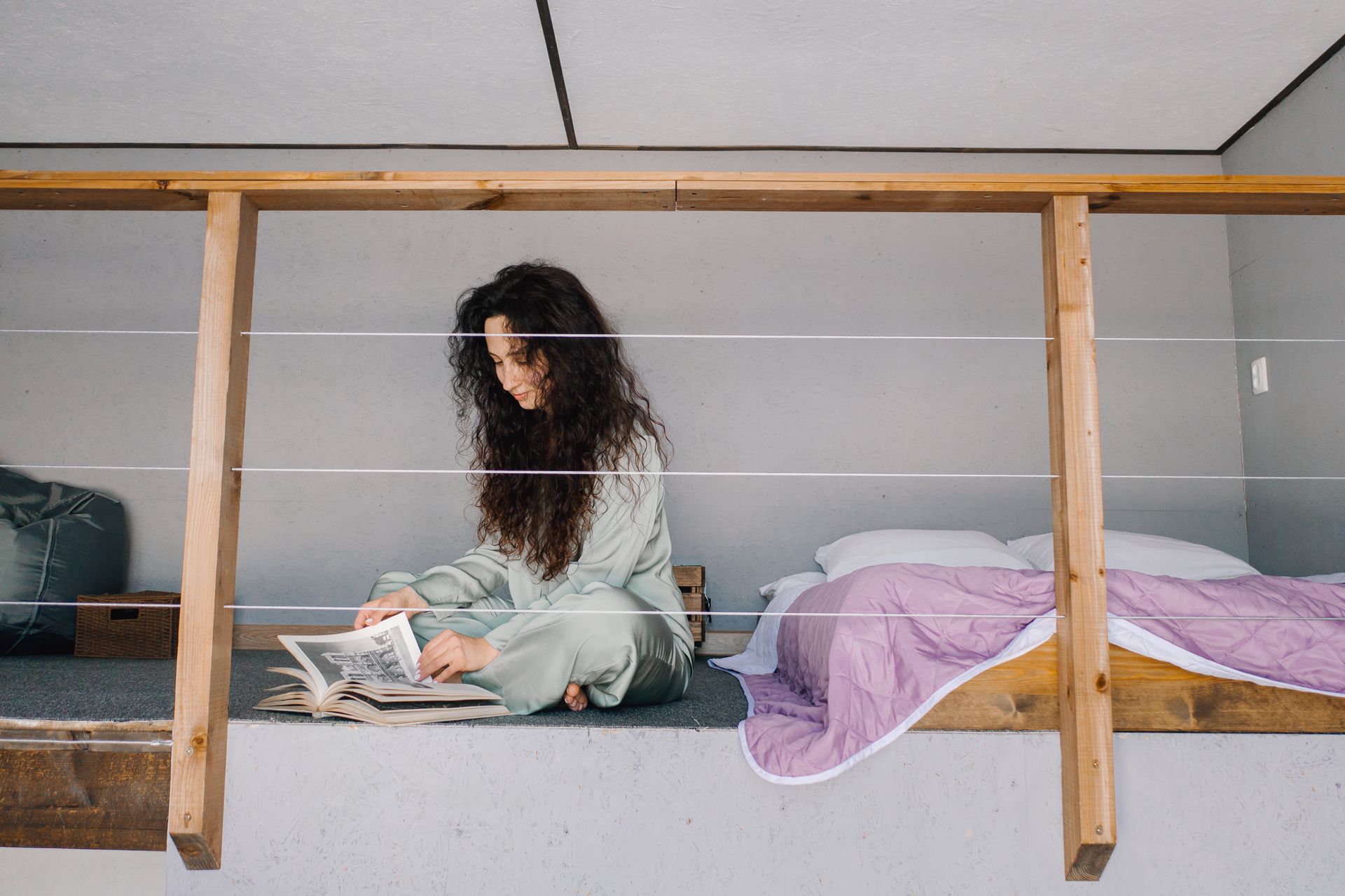 Woman enjoying a quiet moment reading on a comfortable loft bed with natural lighting.