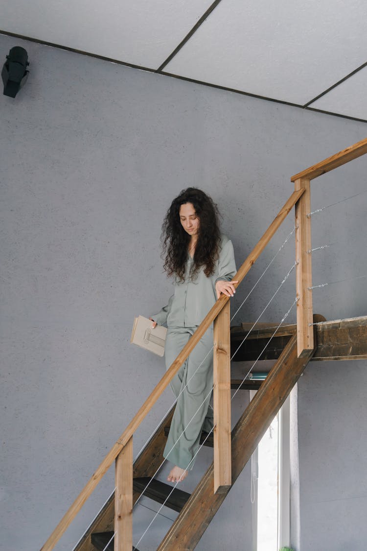 A Woman Going Down The Stairs While Holding A Book