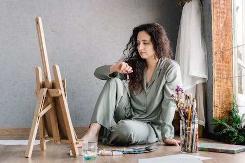 Woman Sitting on the Floor While Holding a Paintbrush