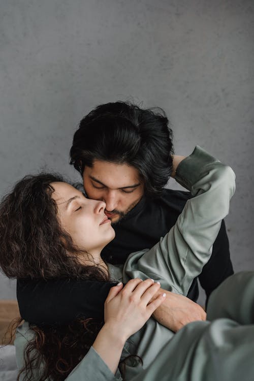 A Woman Lying on Bed Beside a Man Playing the Ukulele · Free Stock Photo