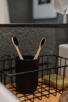 Close-up of two eco-friendly bamboo toothbrushes in a modern bathroom setting.