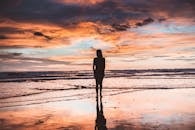 在尼加拉瓜马塔加尔帕的海滩上，一名女子的剪影映衬在充满活力的日落天空下