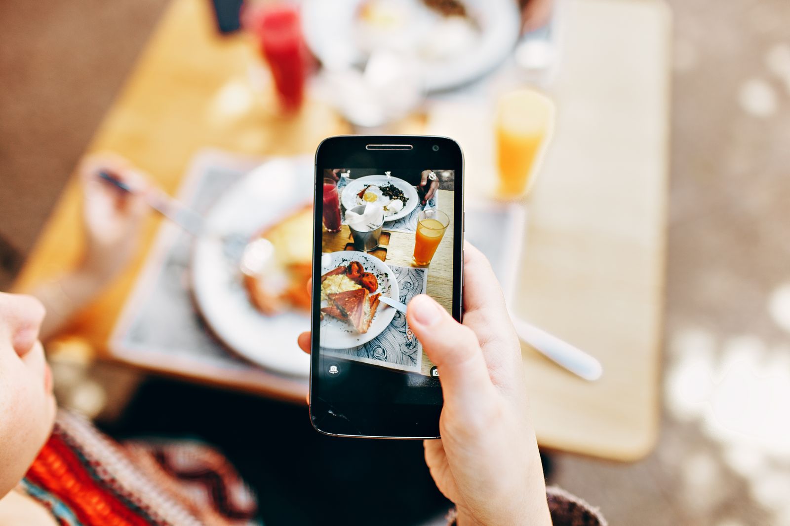 Person photographing a plated meal with a smartphone for social media