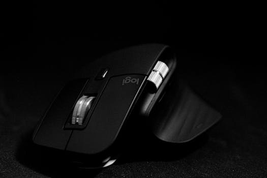 Close-up of a sleek black wireless computer mouse against a dark background, highlighting its design.