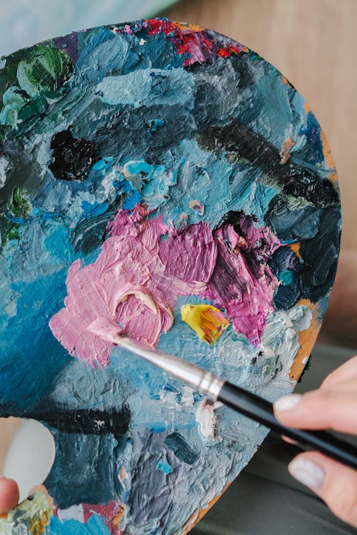 Close-Up Shot of a Person Holding a Palette and a Paintbrush