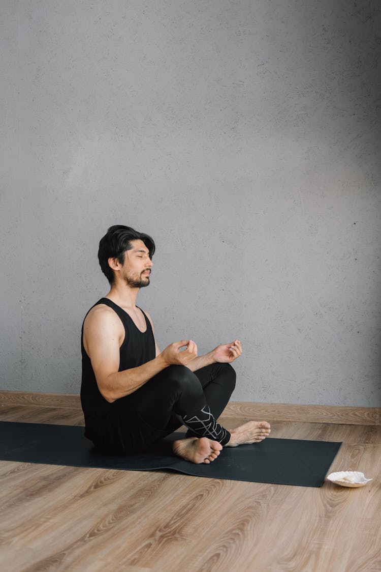 A Man In Black Activewear Doing A Meditation On A Yoga Mat