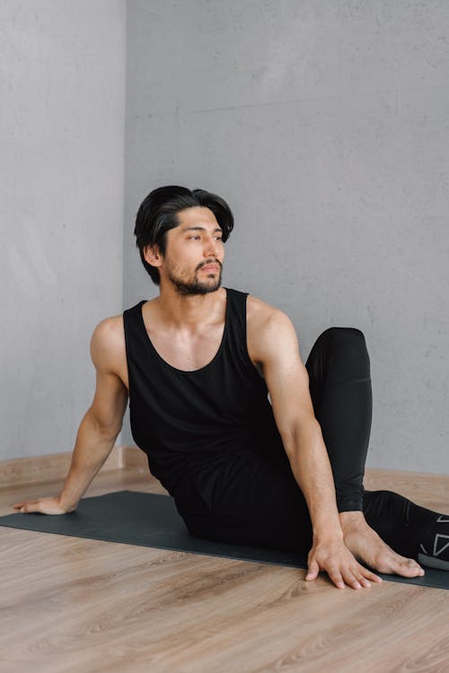 Photo of a Man in a Black Tank Top Doing Yoga