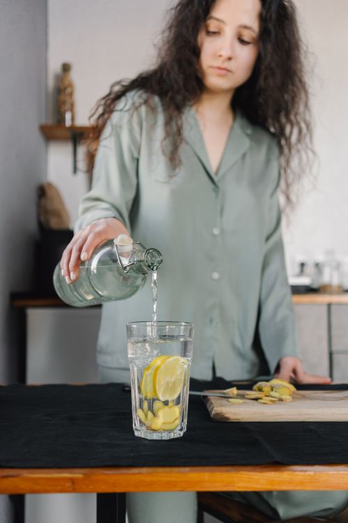 Free Healthy drink preparation with lemon and ginger by a woman indoors. Stock Photo