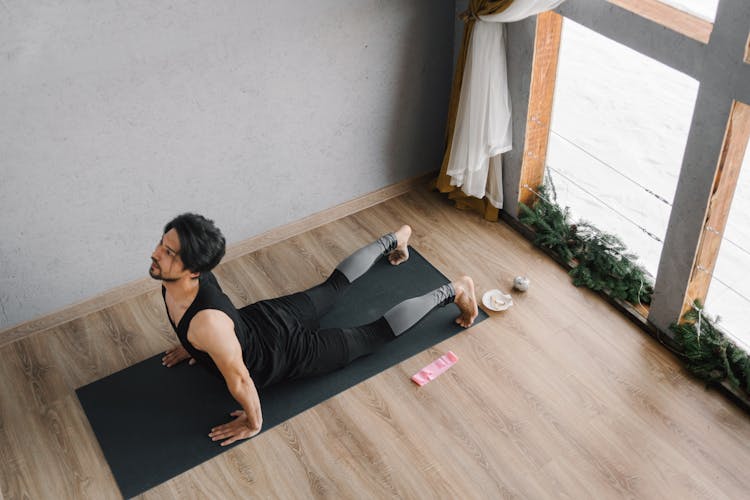 A Man In Black Top Doing Yoga At Home