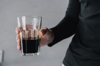 Person Holding Clear Shot Glass With Black Liquid