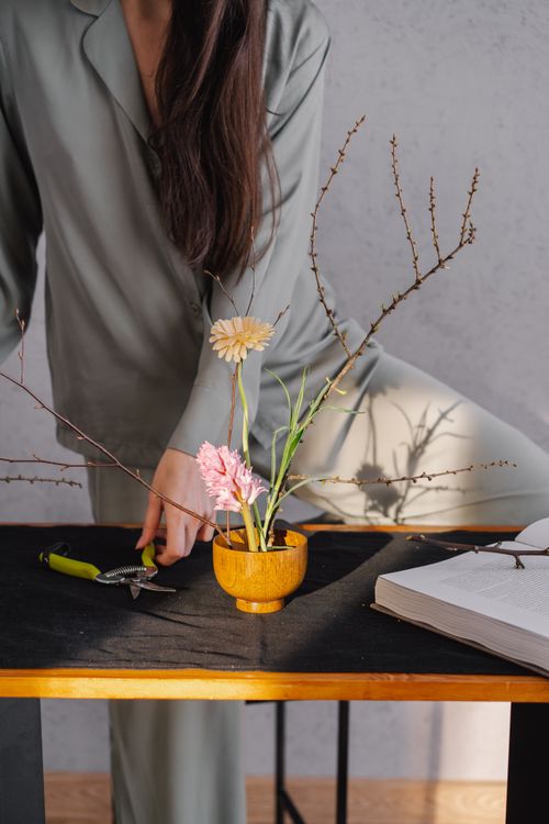 Free Woman arranging flowers on a table, embracing mindful home routines. Stock Photo
