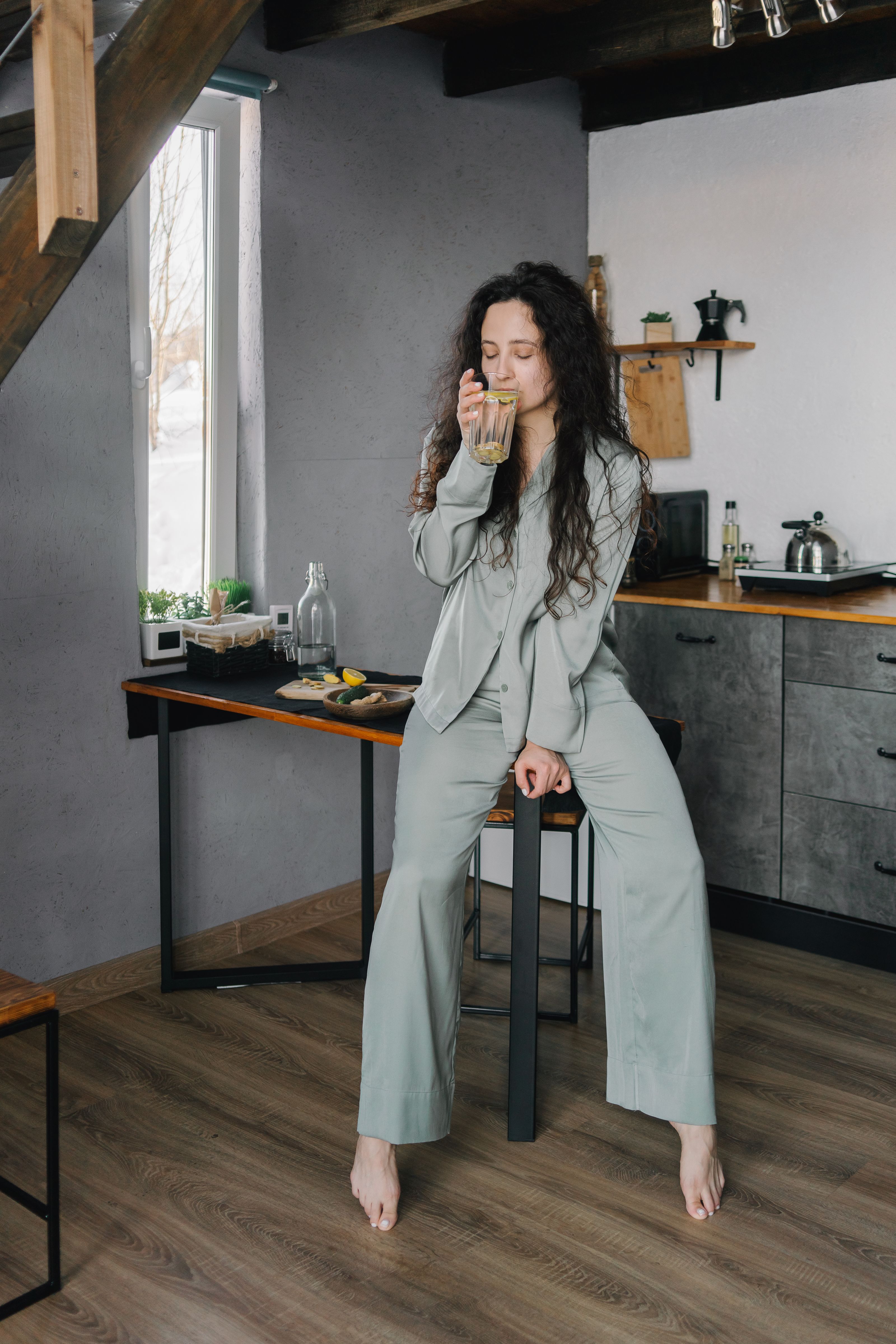 Uma mulher desfruta de uma bebida relaxante em uma cozinha aconchegante, promovendo relaxamento e atenção plena.