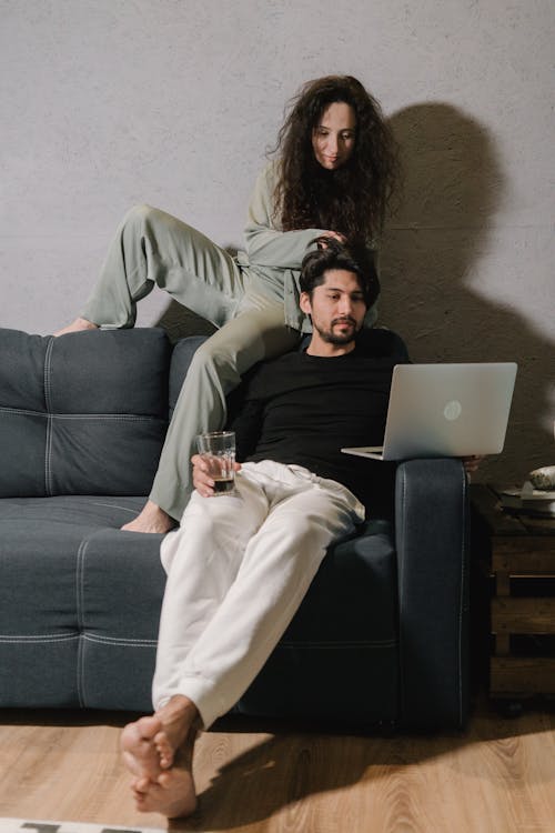 Young couple watching film on netbook while resting on couch at home