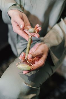 Close-up of hands holding a jade roller massager in a serene setting, perfect for skincare routines.