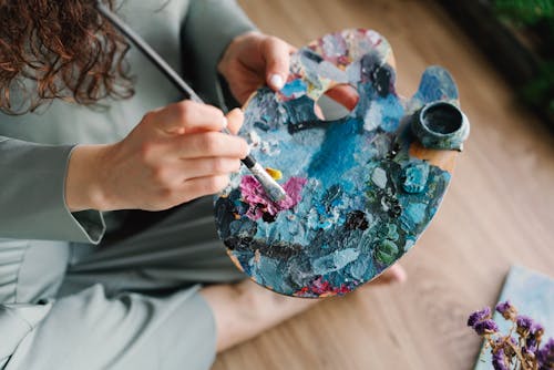 Free A Person Holding a Brush and Palette with Colorful Paint Stock Photo