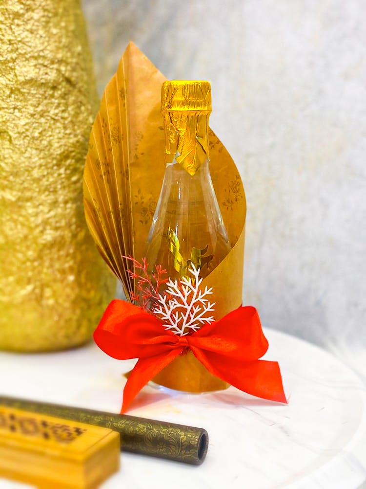 A Glass Bottle Wrapped With Gold Wrapper