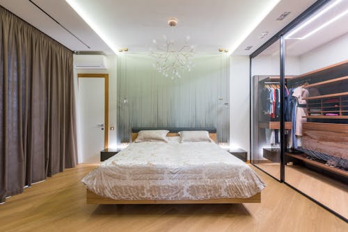 Interior of elegant bedroom with cozy bed and wardrobe with glass doors