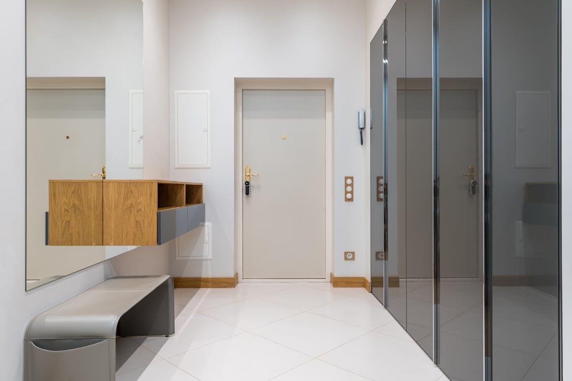 Free Wooden shelf with bench placed in front of wardrobe with mirrored doors in corridor of modern apartment Stock Photo