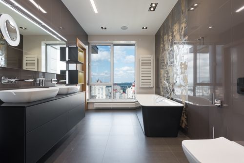Free Wooden furniture with bathtub and ceramic sinks and toilet bowl in contemporary master bathroom with big windows in daylight Stock Photo