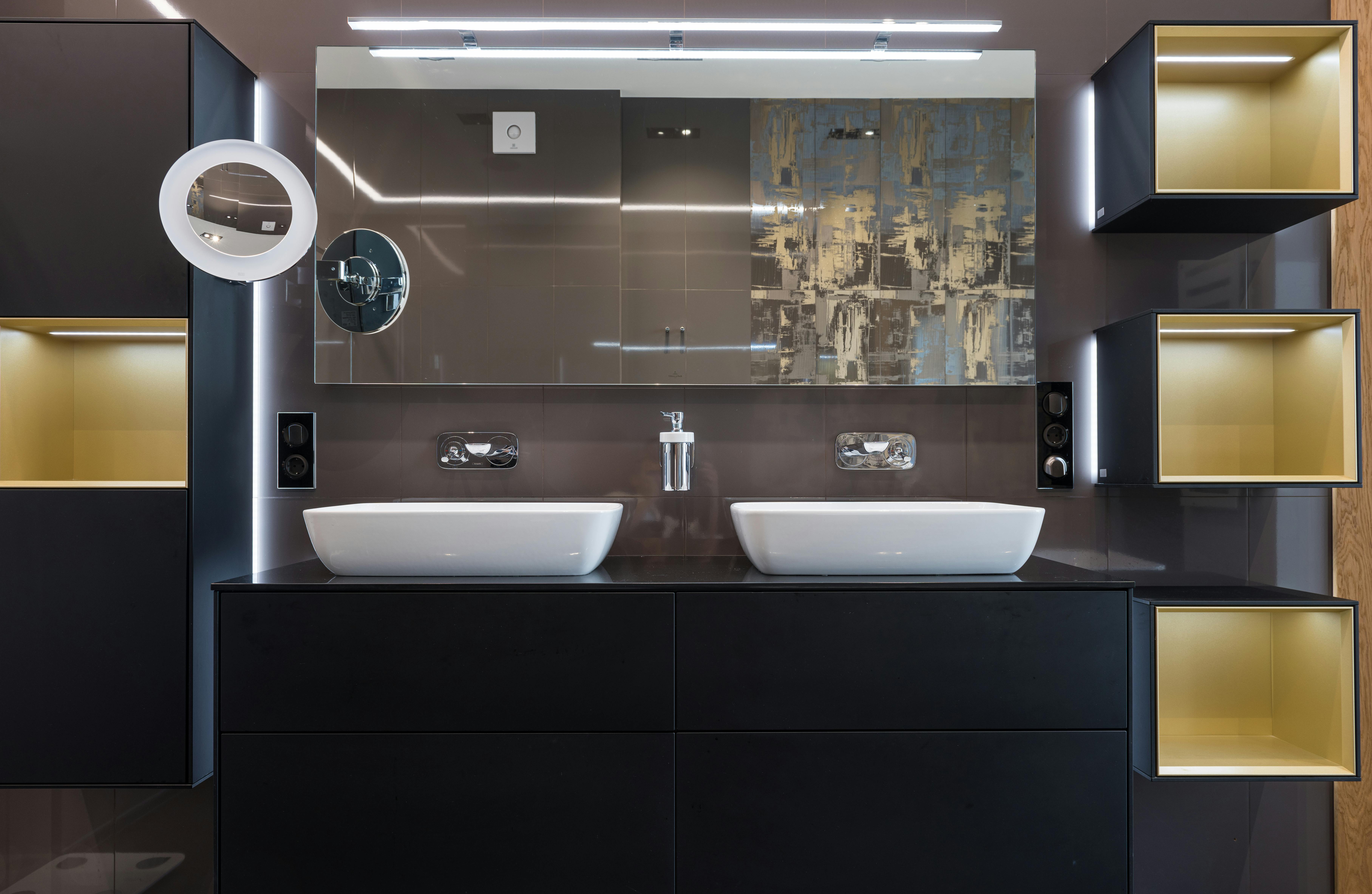 white sinks placed on wooden cabinet in contemporary illuminated bathroom