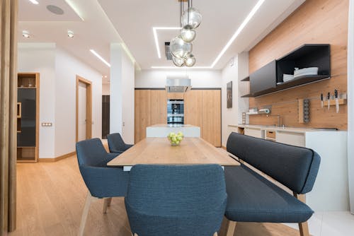 Dining zone with wooden table and soft chair and cushion placed in modern kitchen of spacious apartment