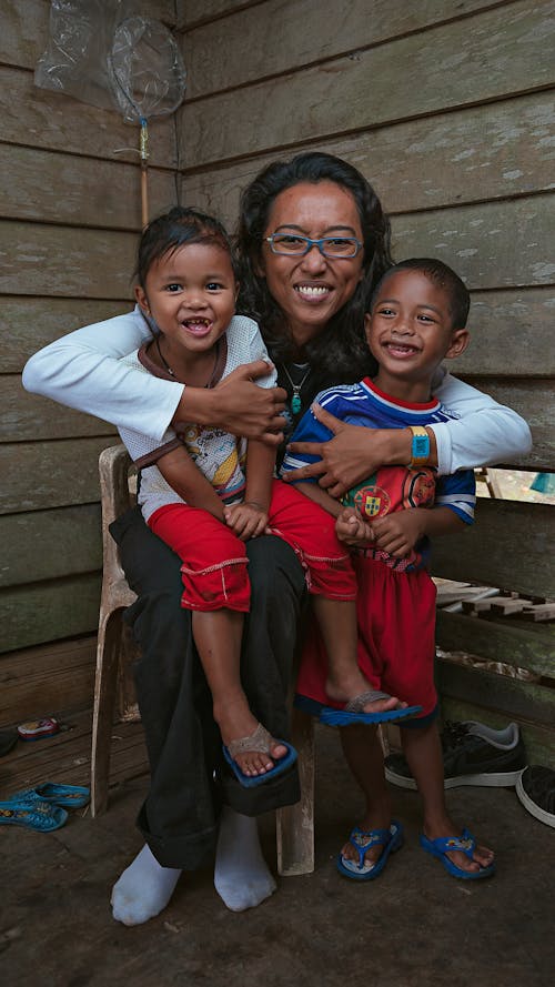 Happy ethnic mother embracing children in house