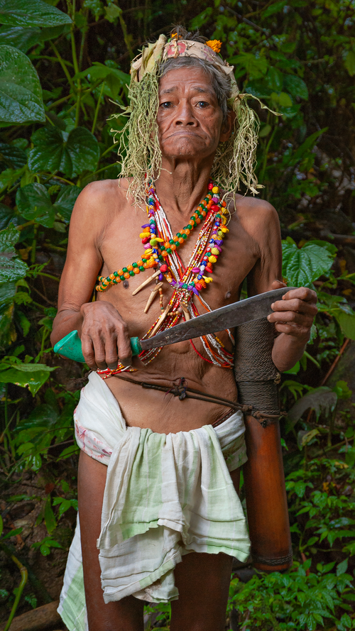 Free Senior ethnic male in loincloth and traditional accessories with knife looking at camera in jungle Stock Photo