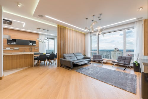 Interior of spacious modern apartment in multistory building with comfortable sofas in living room and kitchen zone with dining table and chairs
