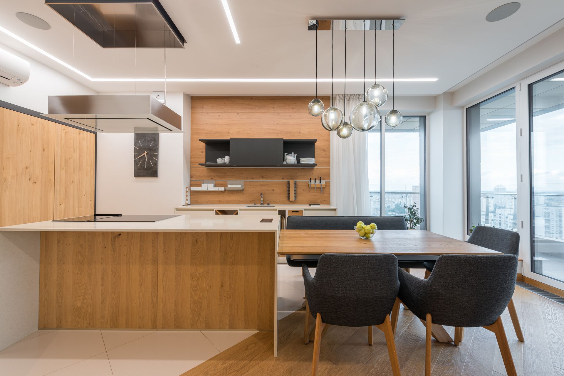 Interior of contemporary large clean kitchen with wooden cabinets and white counter under modern lights in apartment