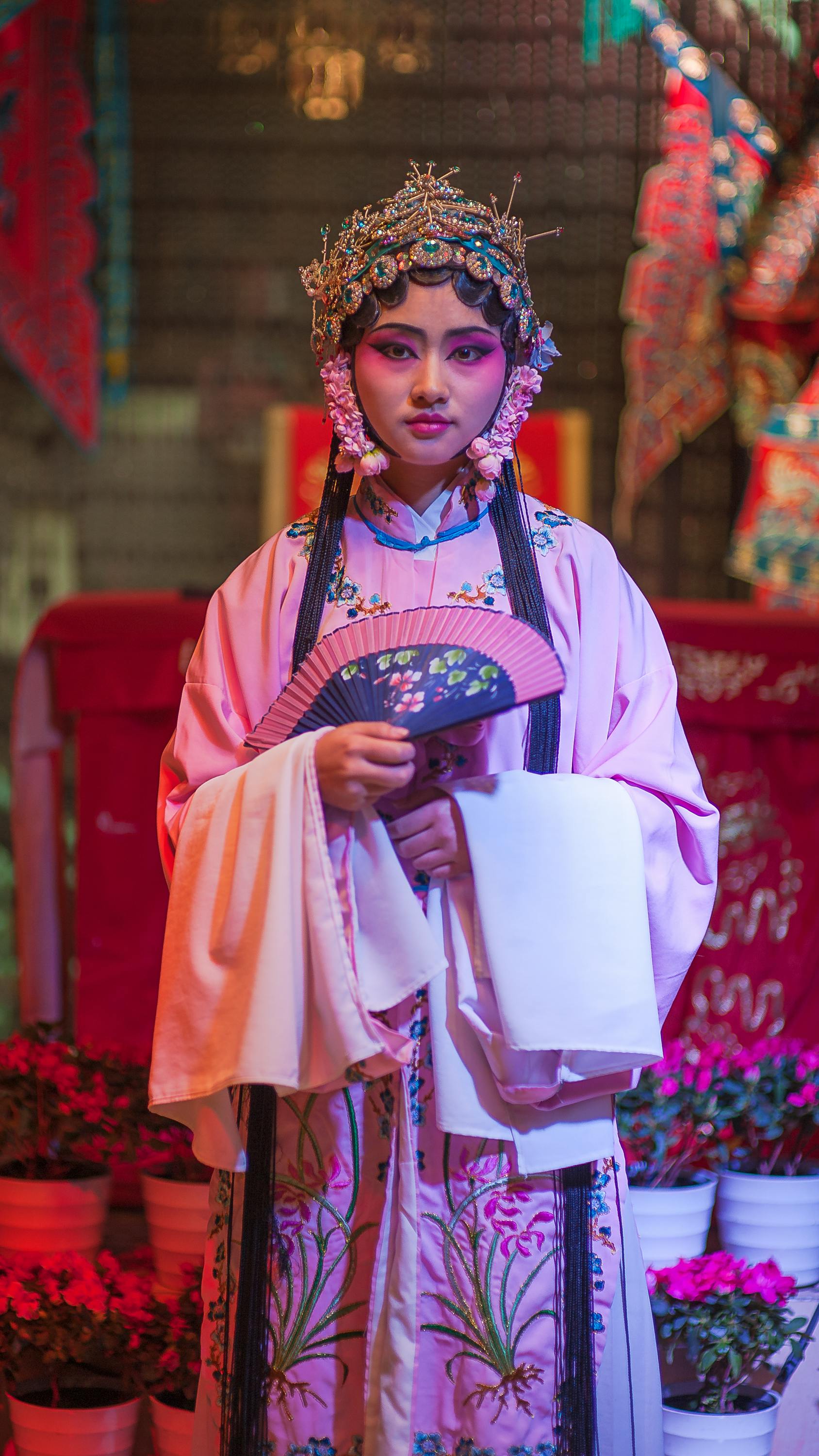 Young ethnic female in crown and traditional wear with floral ornament looking at camera on blurred background